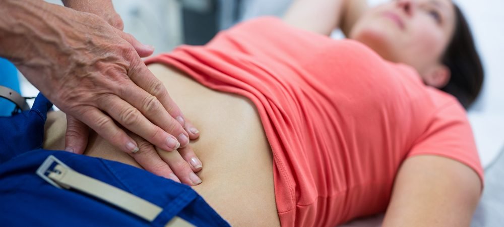 Woman getting ultrasound of a abdomen from doctor in hospital